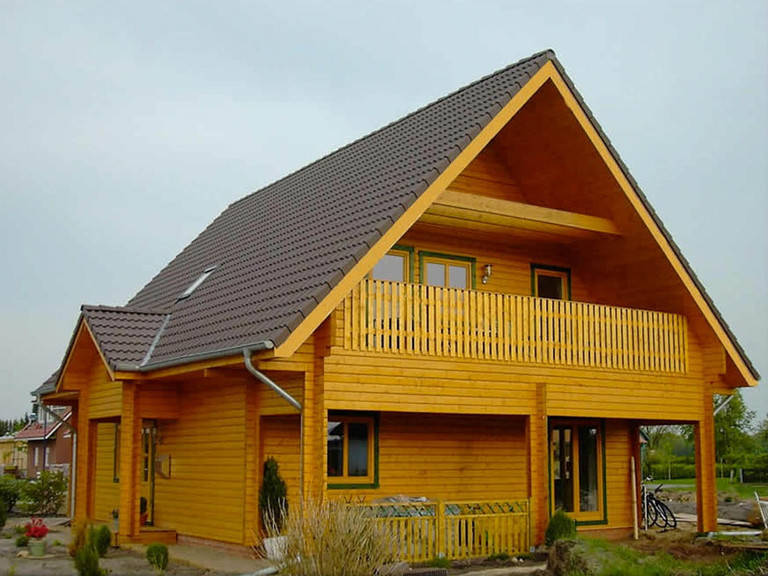 Aussenansicht von der Seite auf den überdachten Hauseingang und den überdachten Balkon unter dem Giebel.